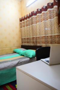a room with a bed and a desk with a laptop at Kompass - Home Stay in Dhaka