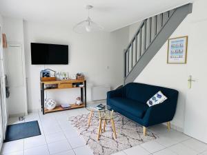 a living room with a blue chair and a tv at Cottage en baie in Cayeux-sur-Mer