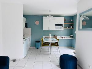 a kitchen with blue walls and a table and chairs at Cottage en baie in Cayeux-sur-Mer +10 photos