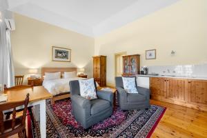 a bedroom with a bed and two chairs and a table at Robe House Heritage Accommodation in Robe