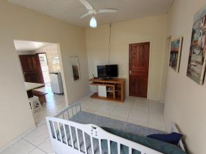 a living room with a crib and a television at Oásis - Casa com Piscina e Churrasqueira in Pontal do Paraná