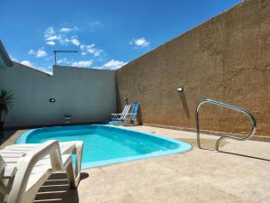 a swimming pool with two chairs next to a wall at Oásis - Casa com Piscina e Churrasqueira in Pontal do Paraná