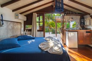 a bedroom with a blue bed and a kitchen at Villa Giulia Morro Residence in Morro de São Paulo