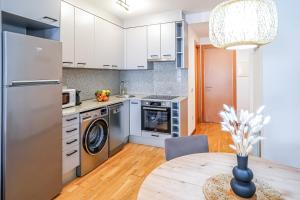 a kitchen with white cabinets and a table with a vase at Allotjament el Pont in Camprodon