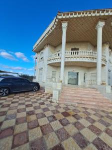 a car parked in front of a building with columns at فيلا الاحلام السعيدة in Ar Ramthā