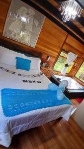 a bedroom with a bed with a blue and white comforter at Pousada Caminho do Lago in Rio Rufino