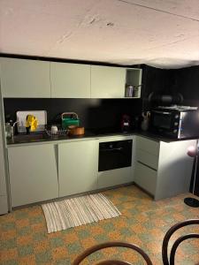 a small kitchen with white cabinets and a microwave at Le refuge boisé in Hérémence