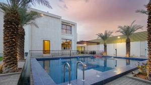 a swimming pool in front of a house with palm trees at قو اب إليت in Abā al Kibāsh