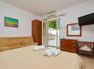 a bedroom with a bed and a couch and a tv at Villa Azure Saplunara in Saplunara