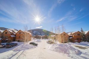 a snow covered street with houses and the sun at Antlers Gulch 303 by SummitCove Lodging in Colorado in Keystone