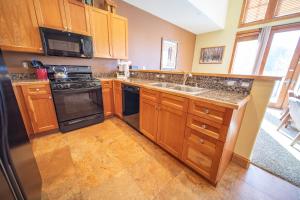 a kitchen with wooden cabinets and a black appliances at Antlers Gulch 303 by SummitCove Lodging in Colorado in Keystone