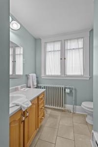 a bathroom with a sink and a toilet and windows at Chic Midstream Studio WiFi Parking in St. John's