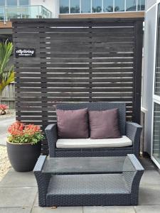 a wicker bench with two pillows on a patio at City Living in New Plymouth