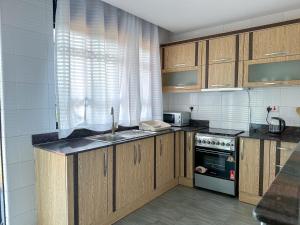 a kitchen with wooden cabinets and a sink and a stove at NL Josephine's Hotel, Apartment in Kampala