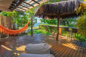 a wooden deck with an umbrella and a hammock at Villa Giulia Morro Residence in Morro de São Paulo