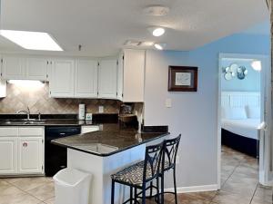 a kitchen with white cabinets and a counter with two chairs at Phoenix III #3146 in Orange Beach