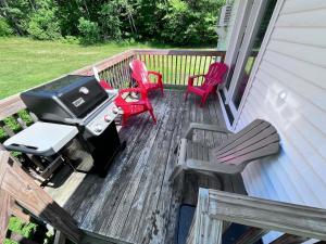 a grill and chairs on a porch with a bbq at Cozy Retreat with Private Backyard Oasis in Livermore Falls