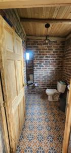 a bathroom with a toilet and a door and a brick wall at Finca El Recuerdo in Guatavita +15 photos