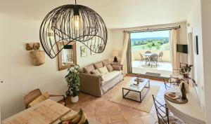 a living room with a couch and a chandelier at Appartement Terrasse avec Vue exceptionnelle Golf in Saumane-de-Vaucluse