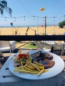 a plate of food with french fries on a table near the beach at Chrish Residence in Negombo