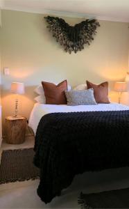 a bedroom with a bed with a black blanket and two lamps at SAGE Cottage Bloubergstrand in Cape Town