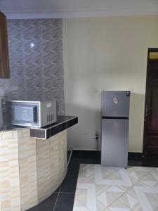a kitchen with a refrigerator and a microwave on a counter at Dorah's Apartment in Entebbe