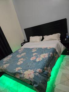 a bed with a blue blanket with flowers on it at Dorah's Apartment in Entebbe