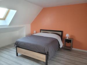 a bedroom with a bed with an orange wall at Lacavee in Le Tréport