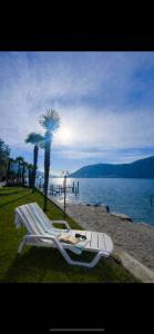a lounge chair on the beach next to the water at Charming Suite am Luganersee, Pool, Parkplatz in Bissone