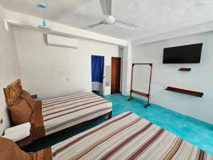 a room with two beds and a flat screen tv at Alojamiento Turquesa in Barrio Nuevo
