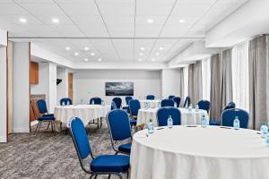 a conference room with round tables and blue chairs at Staybridge Suites - Calgary Airport by IHG in Calgary +96 photos