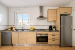a kitchen with wooden cabinets and a stainless steel refrigerator at Sa Tuna - Delta de l'Ebre in Riumar