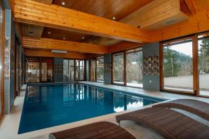a swimming pool in a house with wooden ceilings at Greenhouse Klara with heated pool in Tršće