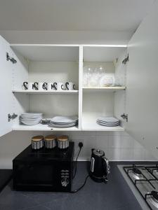 a kitchen with white cabinets with plates and dishes at Two Bedroom Flat Bristol in Shirehampton