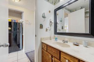 a bathroom with a sink and a mirror and a refrigerator at Coastal condo with shared pool beaches shopping in Fort Walton Beach