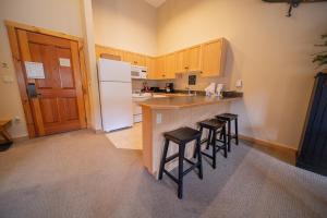 a kitchen with a counter with stools and a refrigerator at Buffalo Lodge 8411 by SummitCove Lodging in Colorado in Keystone