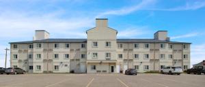 a large building with cars parked in a parking lot at Wilshireinn Hotel in Claresholm