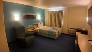a hotel room with a bed and a chair at Wilshireinn Hotel in Claresholm