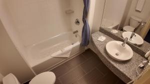a bathroom with a sink and a tub and a toilet at Wilshireinn Hotel in Claresholm +21 photos