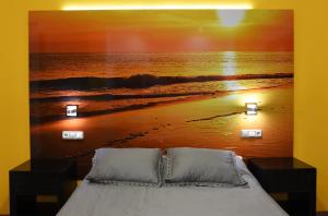 a bedroom with a bed with a picture of a beach at Hostal Boutique El Patio Lepe in Lepe +66 photos