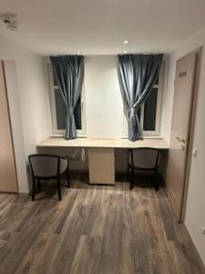 a room with a desk and two windows with curtains at Kurvilla Apartments in Landstuhl