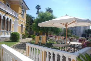 a white fence with tables and an umbrella at Hotel Primula in Alassio