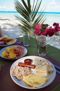 a table with plates of food on a table near the beach at Sun Beach Dhigurah in Dhigurah