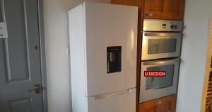 a white refrigerator with a sign on it next to an oven at The Green Yard - Ebike Available for Guests in Sundon
