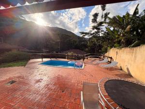 a swimming pool on a brick patio with the sun shining at Refúgio Carangola in Petrópolis +10 photos