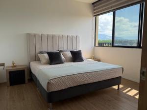 a bedroom with a large bed with a large window at Modern Apartment With Espectacular Panoramic Views in Pereira +34 photos