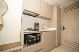 a small kitchen with a stove and a microwave at Refugio Del Mar Bello Horizonte Playa Dormida in Santa Marta