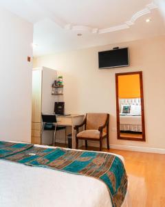 a hotel room with a bed and a table and a mirror at Kuna Hotel in Cuenca