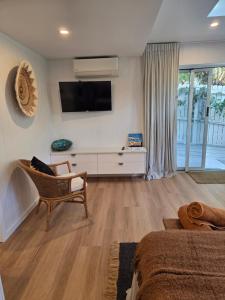 a living room with a tv on the wall and a chair at Seaclusion at Byron in Byron Bay