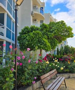 a park bench in front of a building with flowers at Atlantis Resort Nikol in Burgas